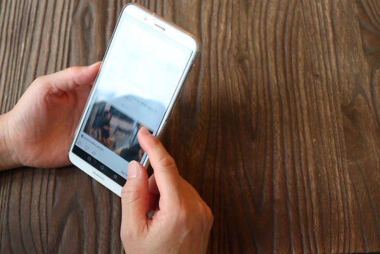 A man swipes a news story on a smart phone.