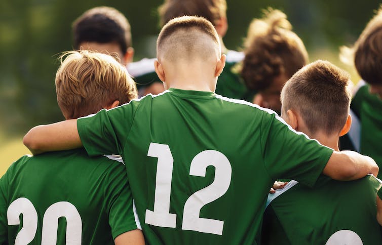 Teen boys in sports kit with arms around eachother