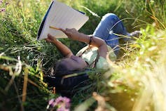 A child seen outdoors with a notebook.