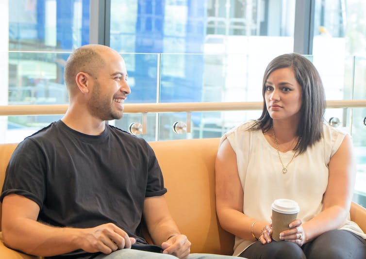 Man smiling sitting beside a woman with an uncomfortable expression