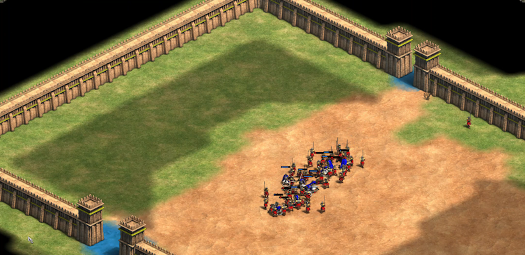 In a video game, a group of nine soldiers in blue are surrounded by a larger group of soldiers in red