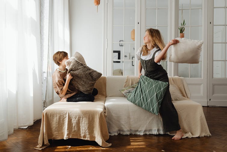 Two children fight with pillows.