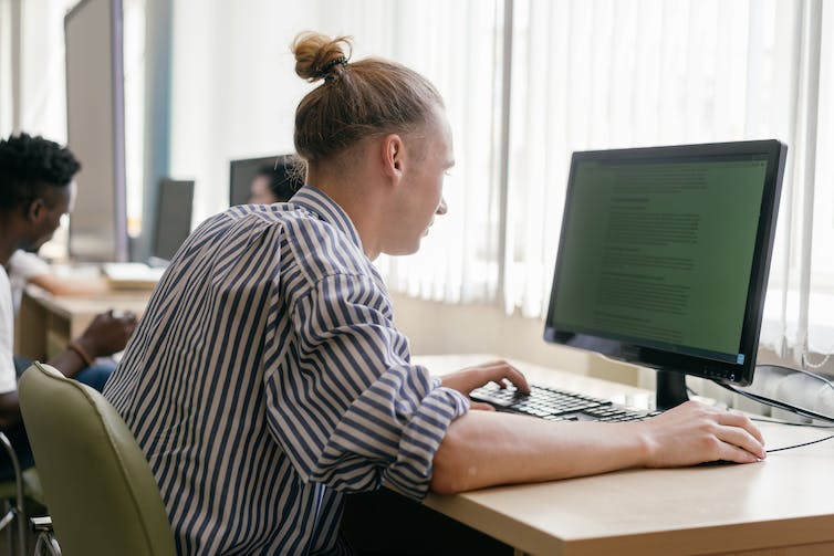 A male student works at a desktop computer.