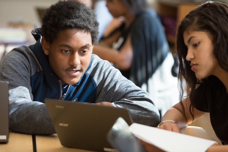 Students seen at a laptop.