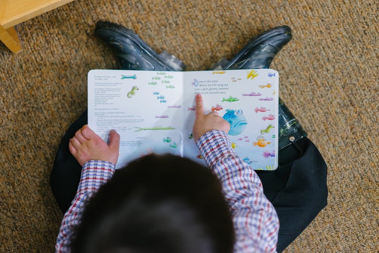 A child seen holding a book.