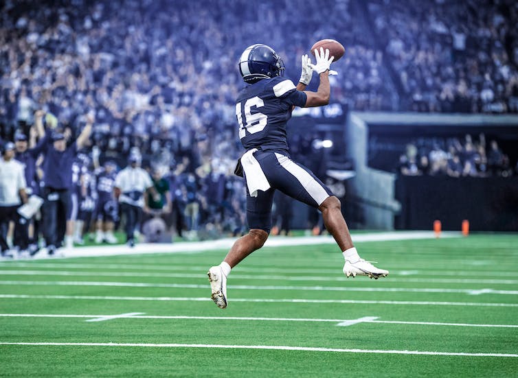 An American football player catches a ball in mid-flight on a field