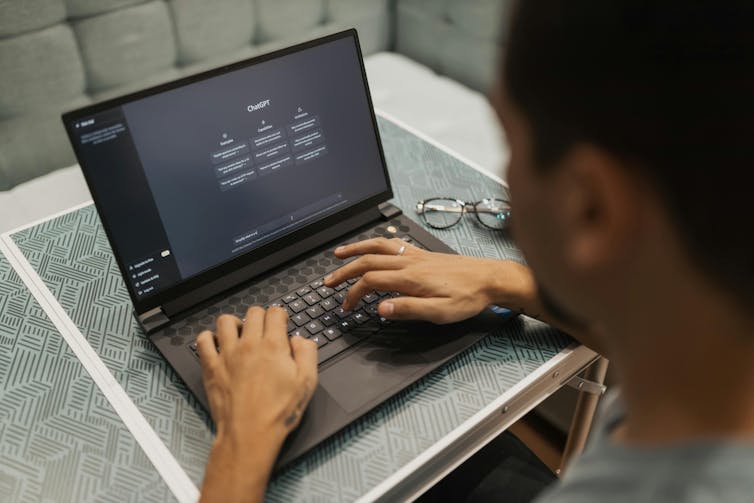 A person working on a laptop with the ChatGPT loading screen displayed.