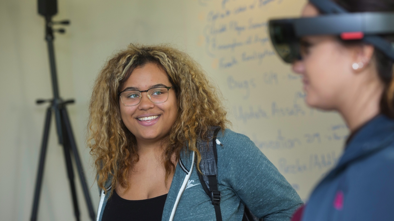 Two female students explore a gaming headset.