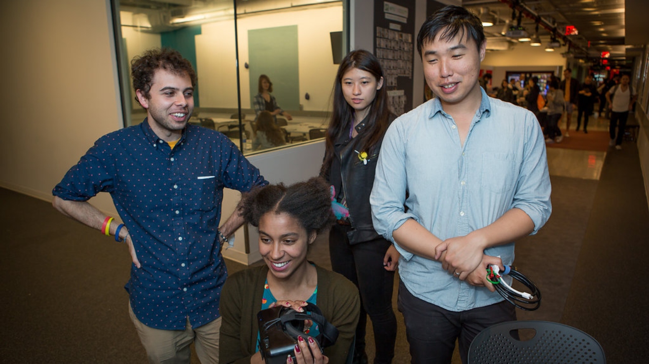 Four students experiment with a gaming headset.