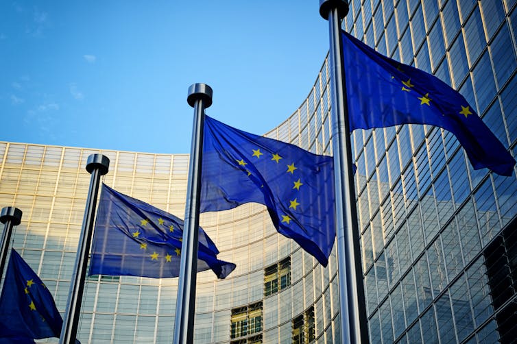 EU flags in front of European Commission in Brussels on a sunny day.