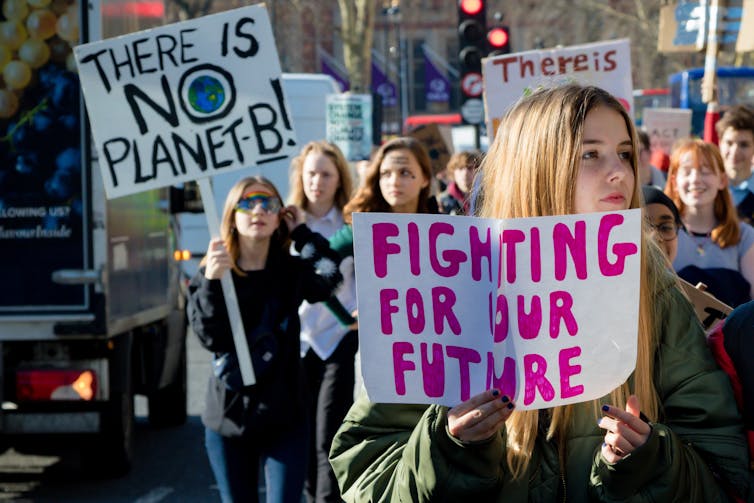 teenagers hold signs at rally