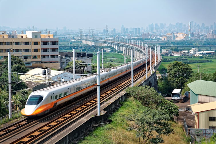 A bullet train passing through a town on a sunny day.