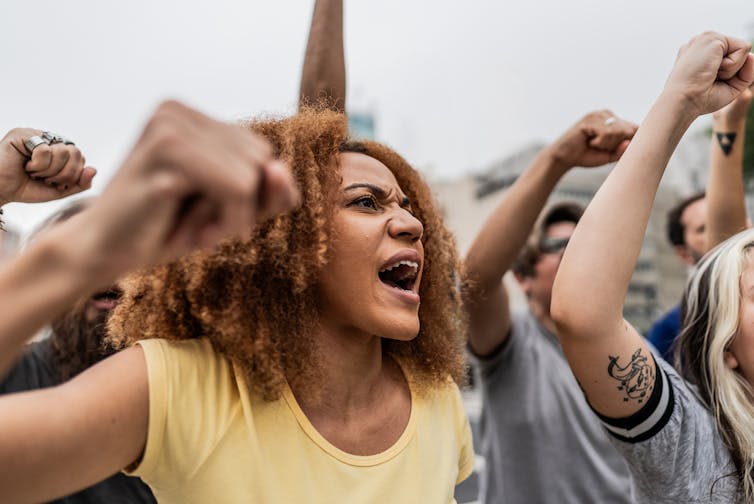 Close-up of group of protestors yelling with their fists in the air