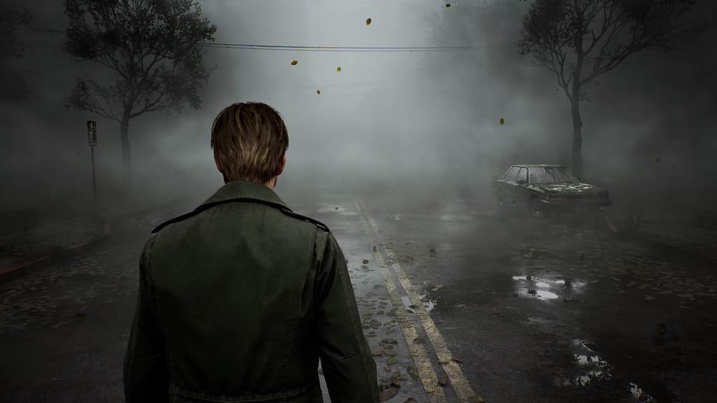 James walks down the middle of a road, towards the fog that obscures the rest of the street from view.