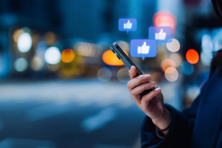 Close up of a person checking smartphone, with thumb-up messages on the screen