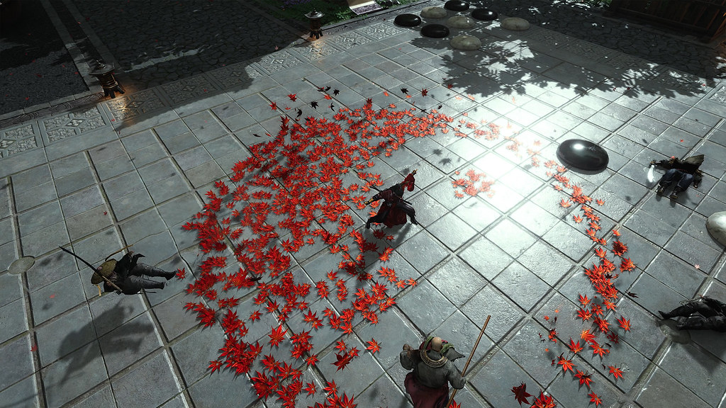 This is an overhead screenshot of a character fighting off multiple opponents. The character is encircled by red leaves on the floor around them, which contrasts sharply with the uniform grey and square tiled floor.