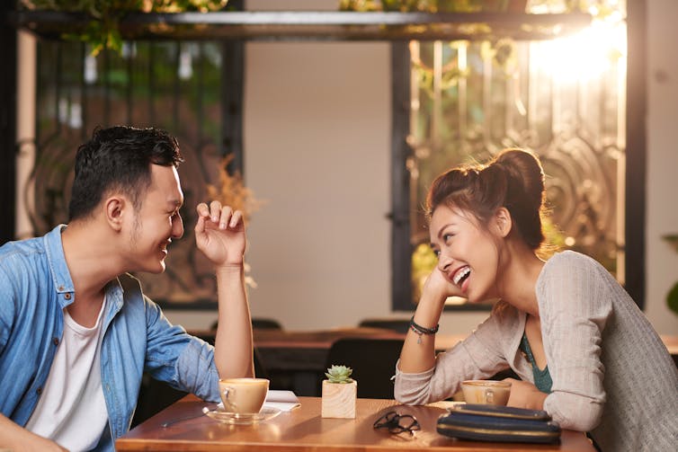 a couple laughs and smiles at each other across a table