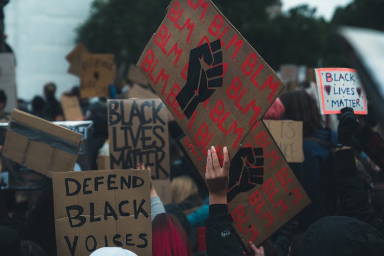 Placards at a protest that say BLM with the raised fist icon.