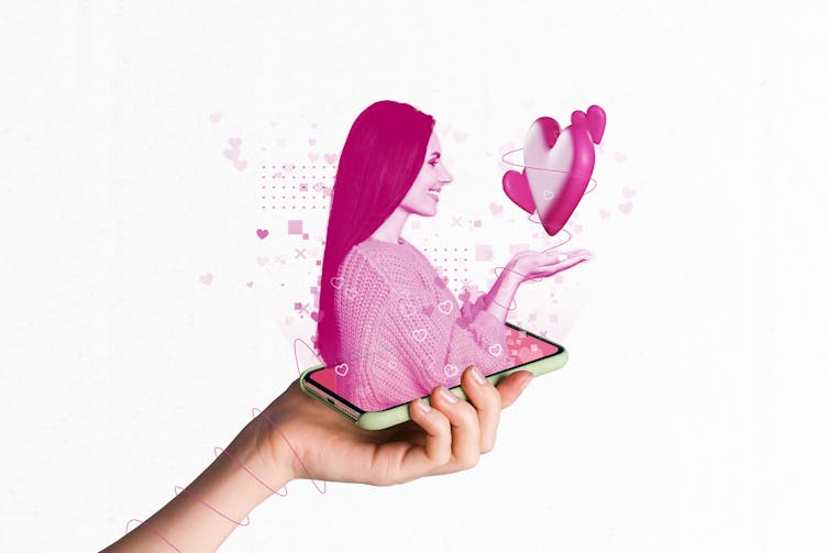 a hand holds a phone with a pink hologram of a woman holding a heart emerging from it