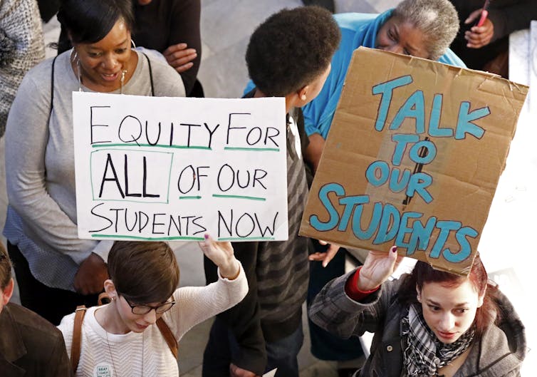 People stand with posters in a crowd