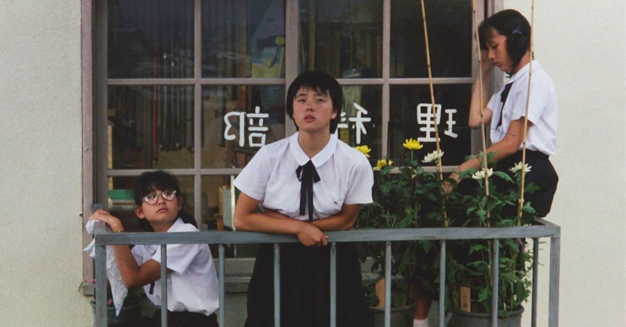 Three teenage girls leaning over a small balcony in Typhoon Club.