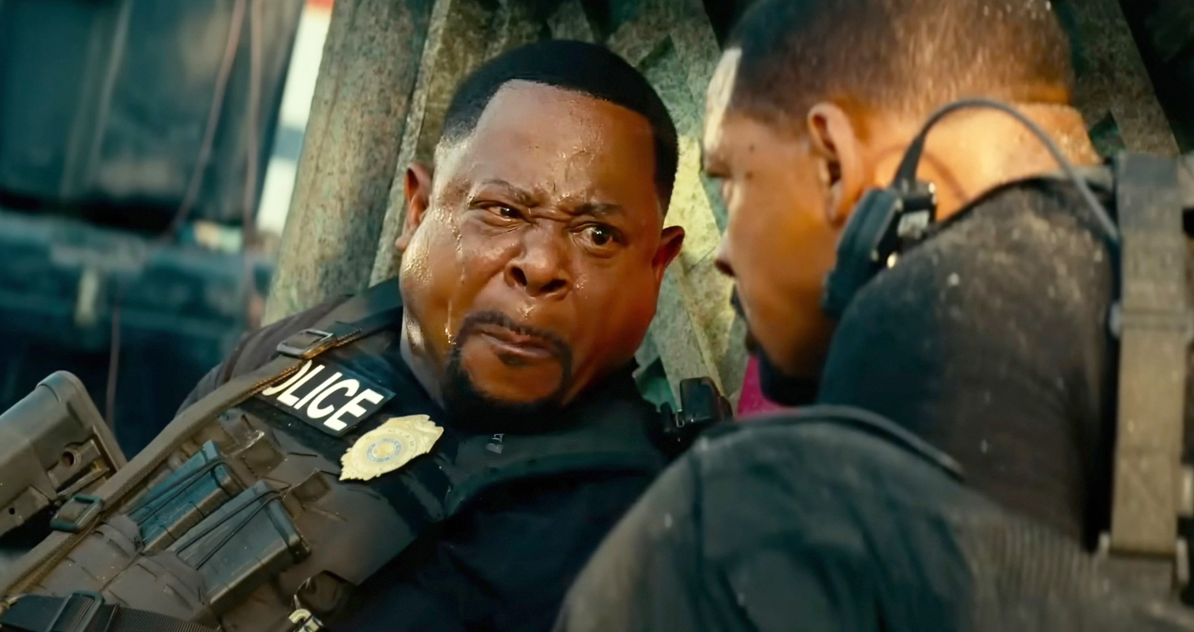 Martin Lawrence makes a really weird “I gotta poop” face, lips pressed together, cheeks puffed out, sweat on his forehead, and one eye squinted as he looks over at Will Smith in Bad Boys: Ride or Die