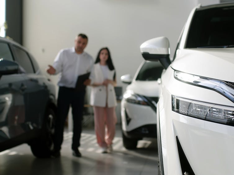 Sales rep showing a woman around a car salesroom