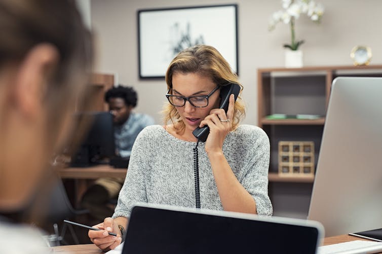 Businesswoman writing while talking on phone