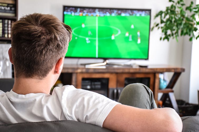 Young man watching soccer game on TV