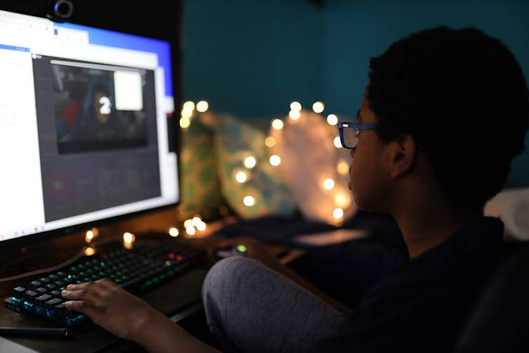 boy sits at computer screen at night