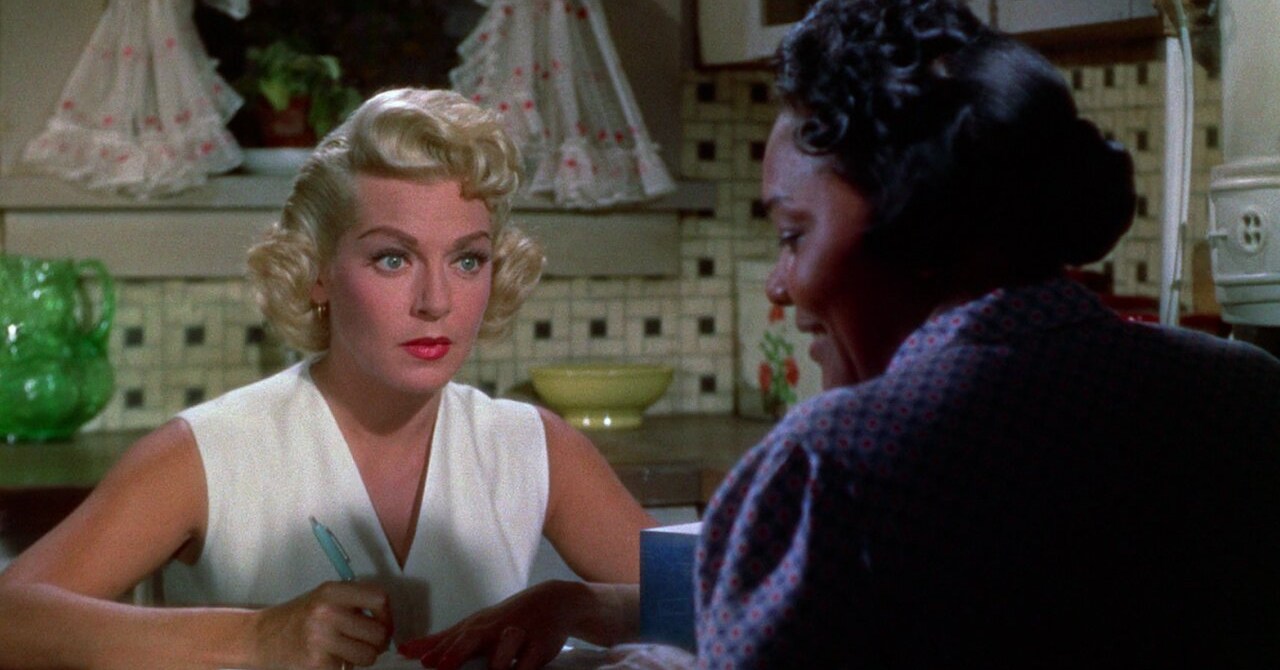 Lora (Lana Turner) and Annie (Juanita Moore) sitting across from each other at a dinner table in Imitation of life (1959).