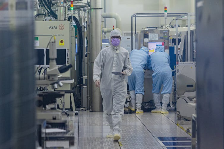 A person in a hazmat suit walks through a lab.