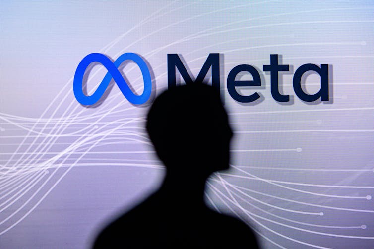 Silhouette of person in front of Meta logo.