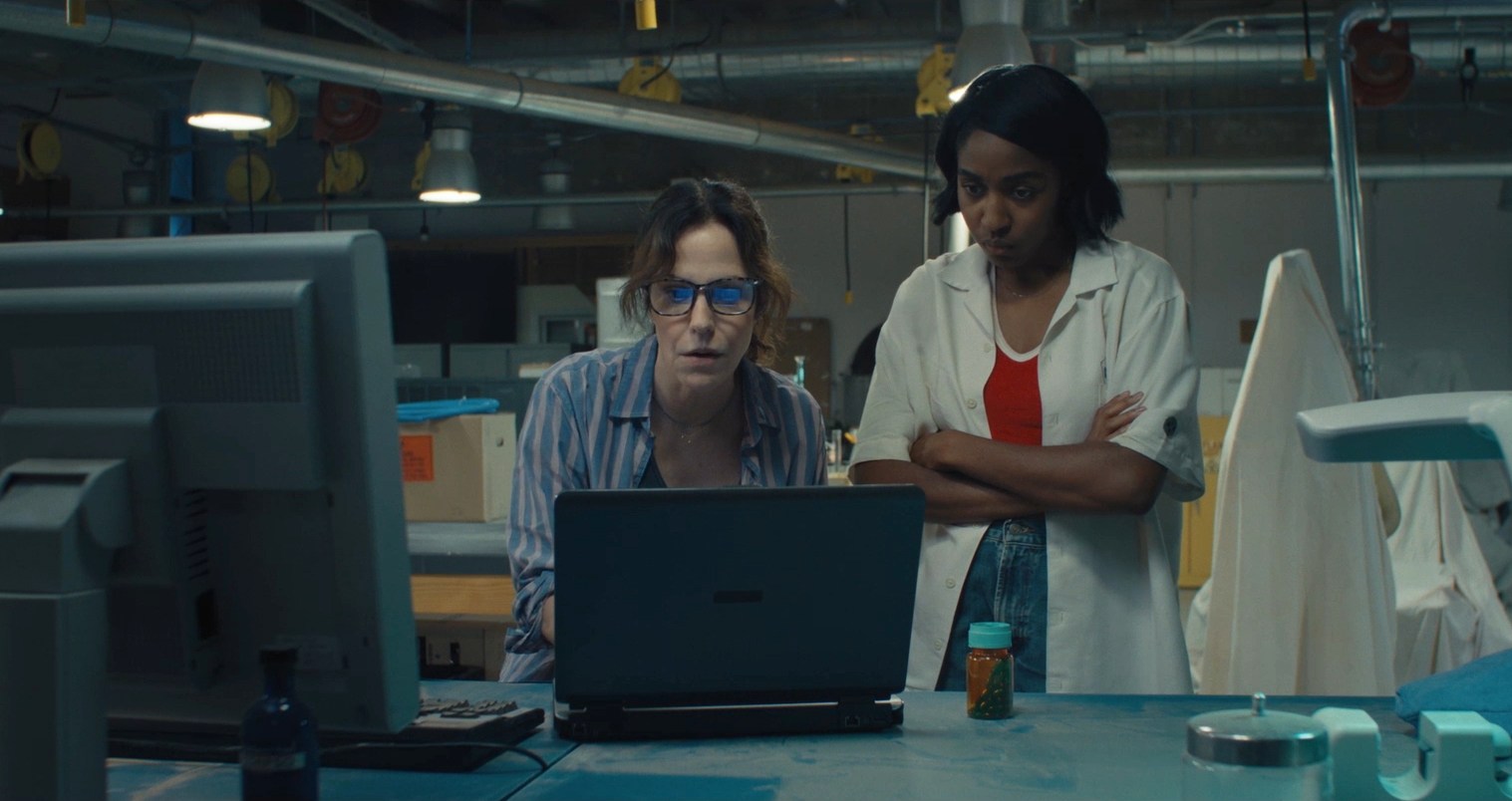 Two woman staring intensely at a computer monitor in a cluttered laboratory in Omni Loop.