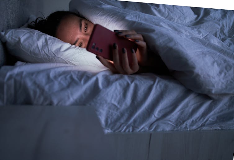 A person laying in bed looking at a phone