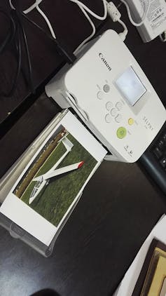 a photograph of an airplane in the output tray of a small desktop printer