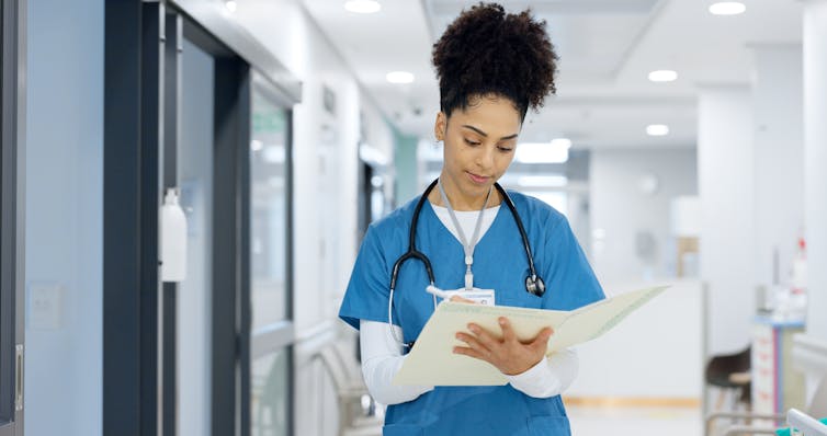 Clinician writes paper notes in a clinic corridor