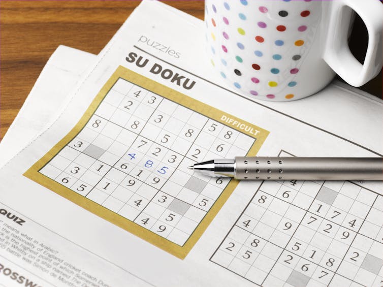 A pen resting on a sudoku puzzle in a newspaper.