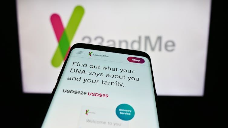 Smartphone with website of US biotechnology company 23andMe Inc. in front of business logo.