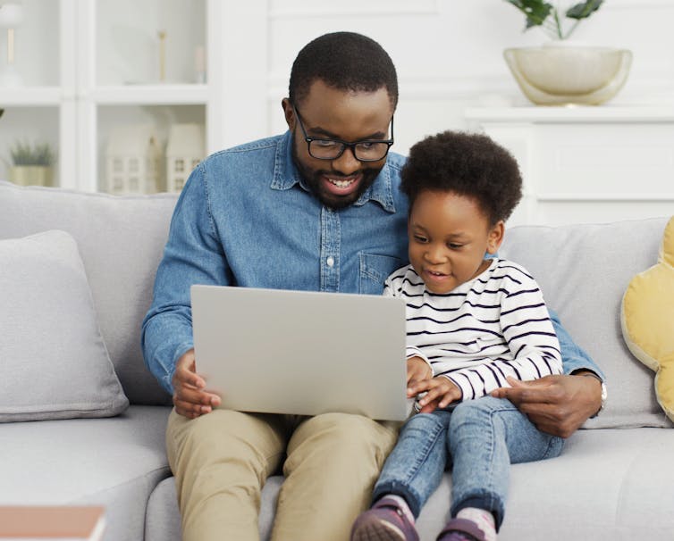 Father and daughter on sofa looking at laptop