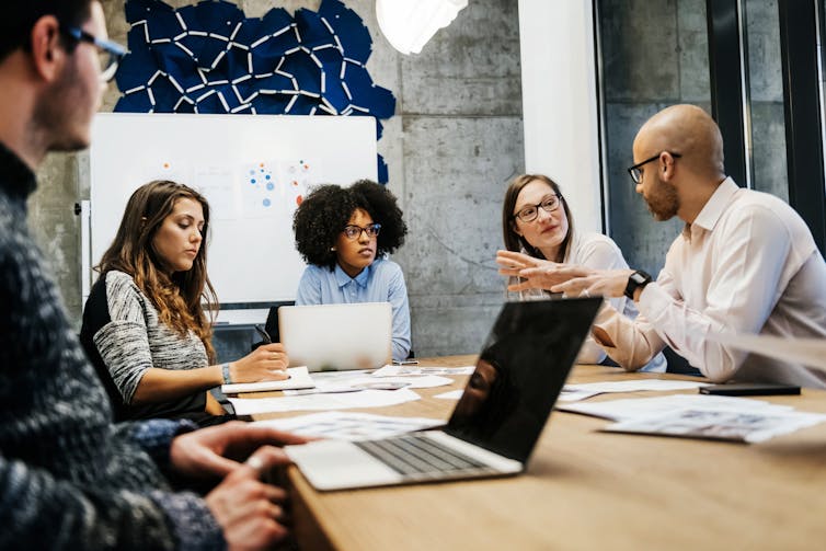 A group of researchers conversing around a conference table.